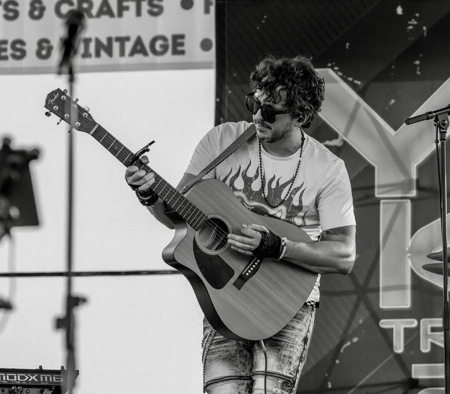 Ray Hartsfield performing on stage with acoustic guitar